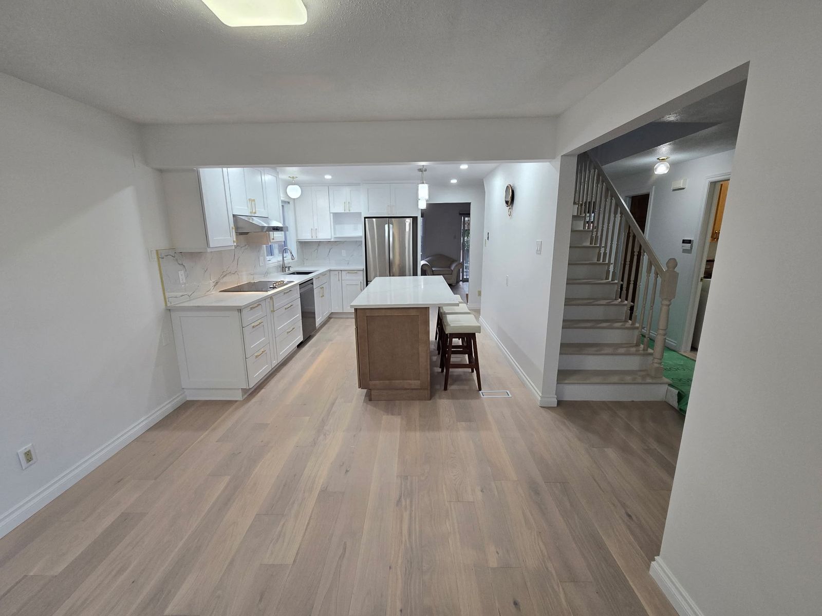 Open kitchen with white Shaker cabinets seen from the hallway