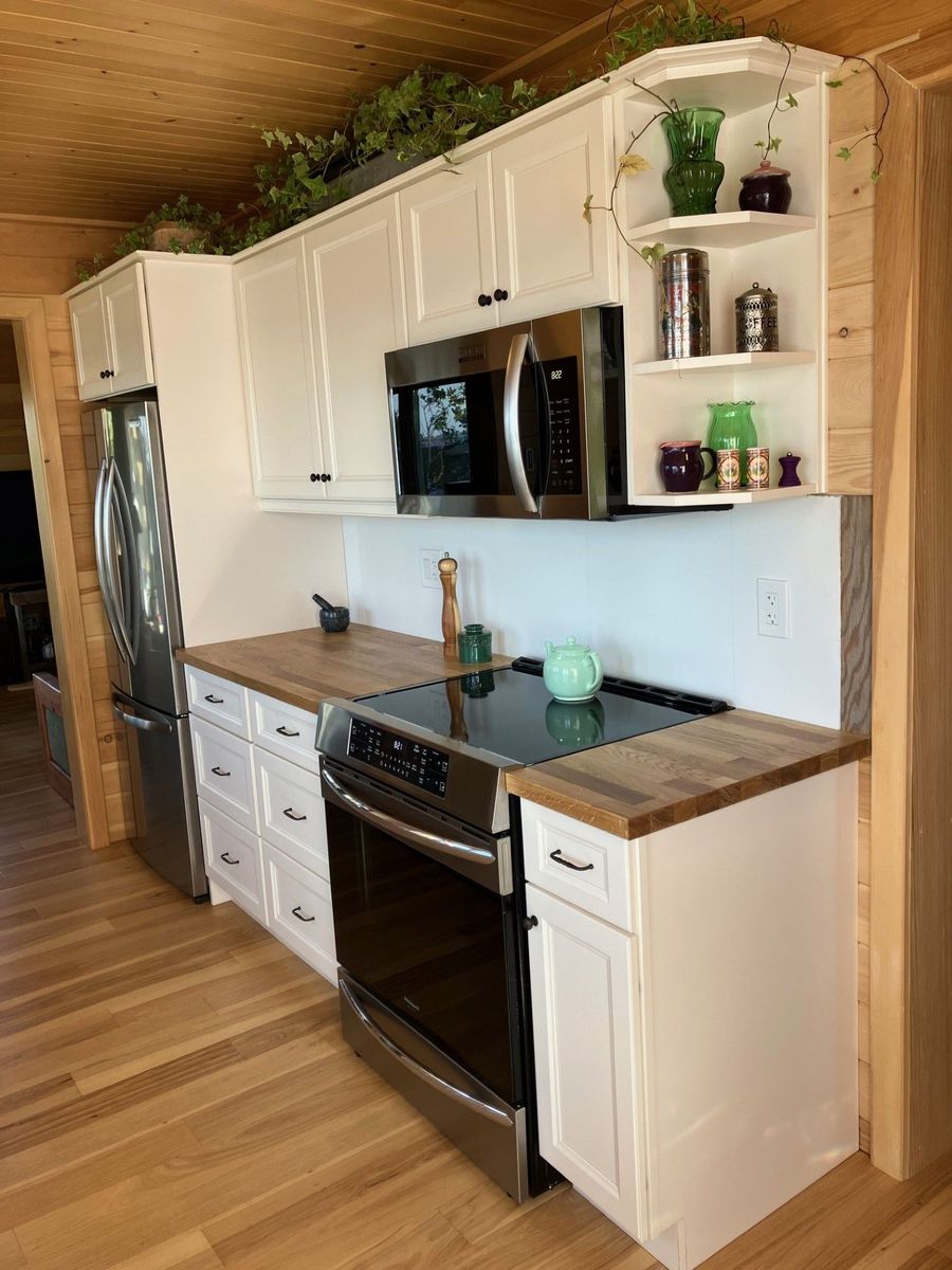 Cottage kitchen with white cabinets, open shelves and a wood counter