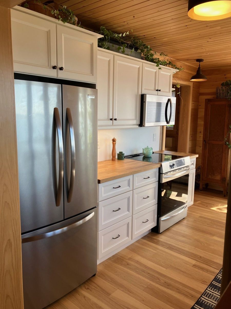Installed white cabinets beside a stainless fridge